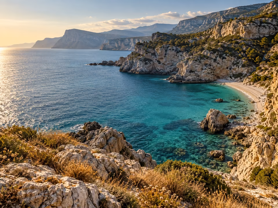 Sunlit coastal headland above calm turquoise water with distant cliffs and fine sea ripples